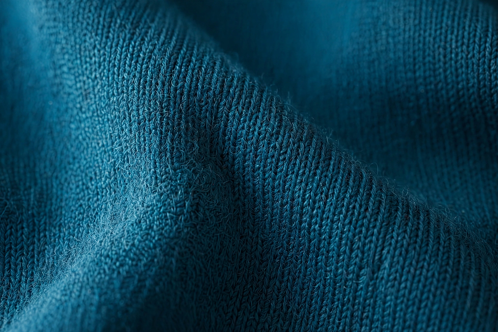 Close-up of teal-blue swim fabric weave showing even knit texture and dye color